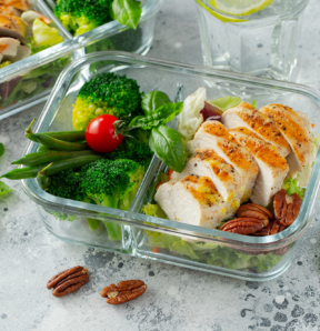 Healthy meal prep containers with green beans, chicken breast and broccoli. A set of food for keto diet in lunchbox on a light concrete background. Top view.