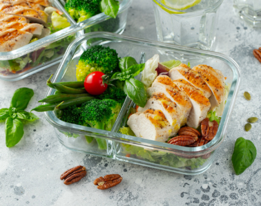 Healthy meal prep containers with green beans, chicken breast and broccoli. A set of food for keto diet in lunchbox on a light concrete background. Top view.
